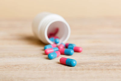 Close-up of pills spilling from bottle on table