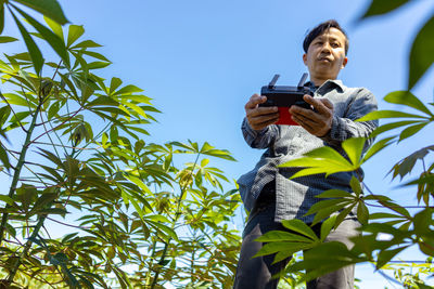 Low angle view of man using smart phone against sky