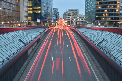 Light trails on road amidst buildings in city at night