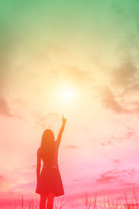 Rear view of silhouette woman against orange sky