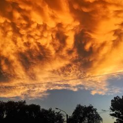 Low angle view of birds flying against dramatic sky