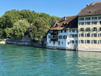 Building by river against clear blue sky