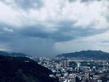 High angle view of buildings in city against storm clouds