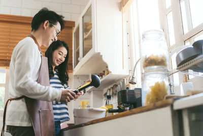 Man with woman preparing pasta in kitchen at home