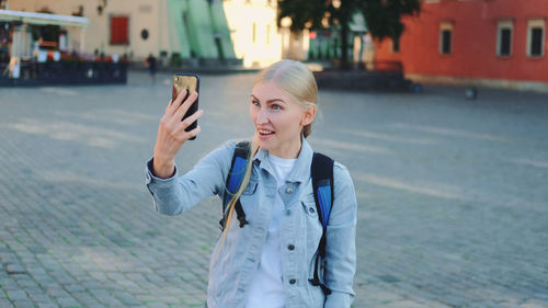 Young woman standing against wall in city