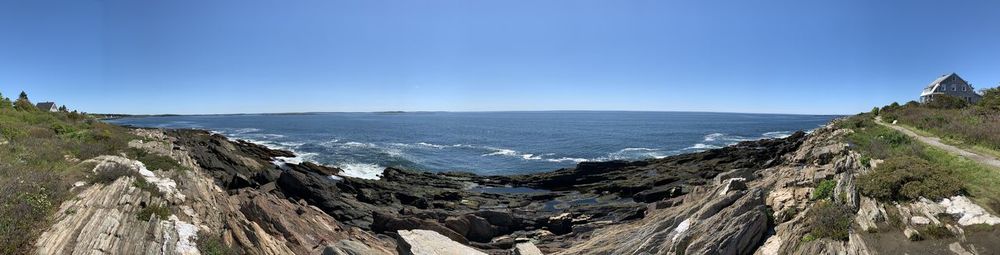 Panoramic view of sea and mountains against clear blue sky