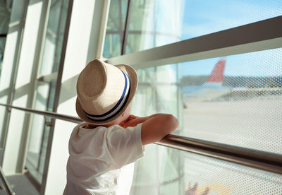 A boy in a straw hat looks at the plane. traveling with children. child in the airport lounge