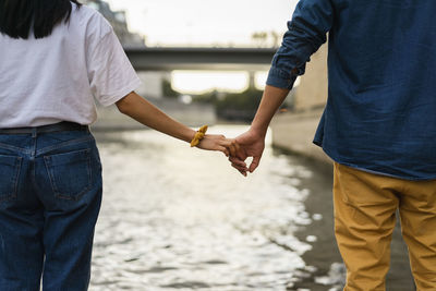 France, paris, couple holding hands at river seine