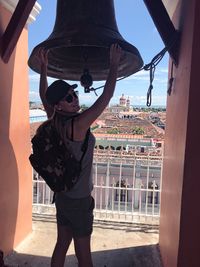 Smiling woman holding bell at church tower in town