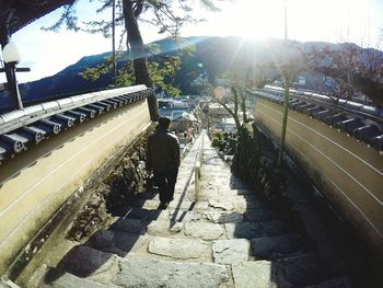 People on steps amidst trees against sky