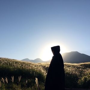 Rear view of silhouette man standing on field against clear sky