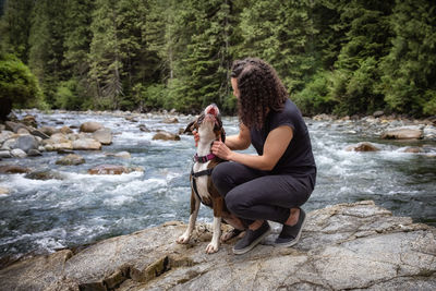 Woman sitting on rock by river in forest