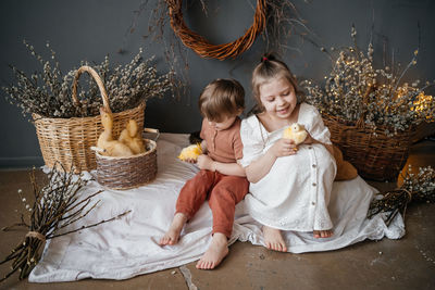 Brother and sister with small goslings in a wicker basket eco style gray willow background