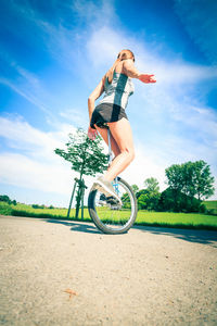 Low angle view of woman riding bicycle on tree against sky