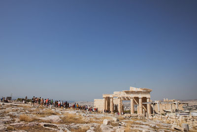 Crowd visiting historic building against clear blue sky