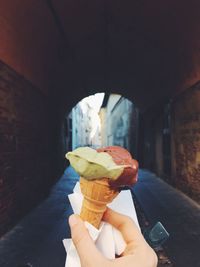 Cropped hand holding ice cream cone outdoors