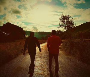 Rear view of silhouette people walking on road against sky