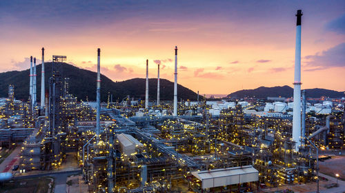 Illuminated industrial buildings against sky during sunset