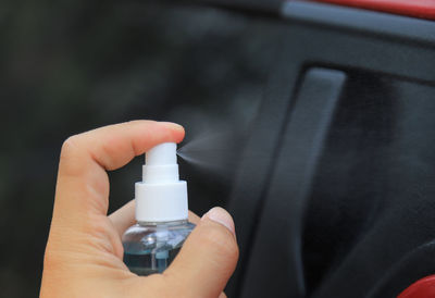 Close-up of person holding bottle against blurred background