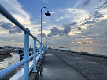 Street light by sea against sky during sunset