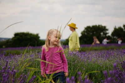 Girl standing amidst flowers on field at farm