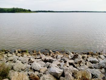 Stones in lake against sky