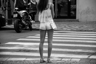 Low section of seductive woman standing on zebra crossing