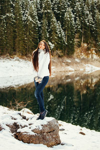 Full length of woman standing on snow against trees