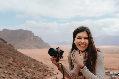 Portrait of woman photographing against sky