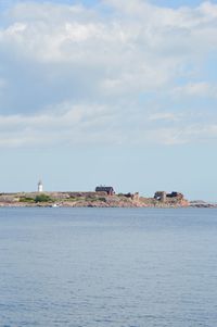 Sea by buildings against sky