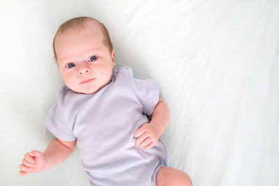 Portrait of cute baby boy lying on bed at home