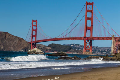 Low angle view of golden gate bridge over sea against clear blue sky