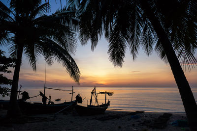 Silhouette boats on beach against sky during sunset