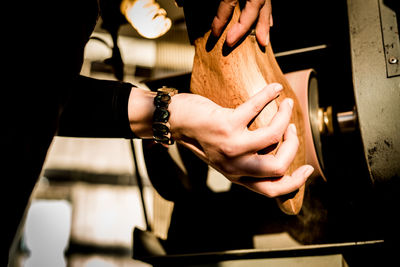 Cropped hands of woman holding wood in workshop