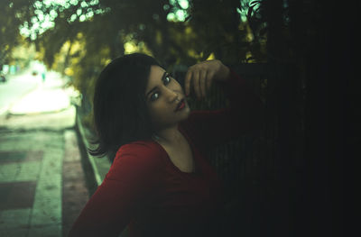 Portrait of woman looking away while sitting on tree