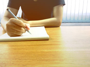 Midsection of person reading book on table