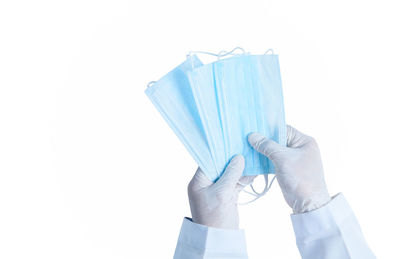 Close-up of hand holding blue umbrella against white background