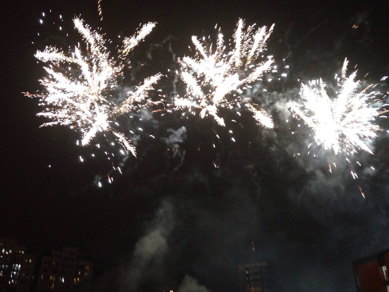 night, illuminated, low angle view, firework display, tree, glowing, sky, exploding, building exterior, built structure, architecture, long exposure, city, light - natural phenomenon, firework - man made object, outdoors, celebration, no people, dark, light