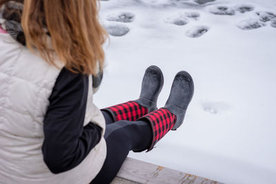 Low section of woman sitting against snow