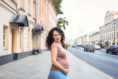 Portrait of smiling young woman standing on street in city