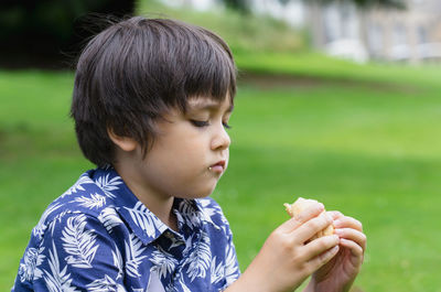 Close-up of boy eating food at park