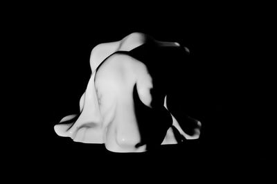 Close-up of woman wearing mask against black background