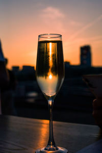 Close-up of wine glass on table against sky during sunset