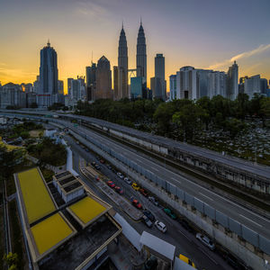 Petronas towers amidst buildings in city during sunset