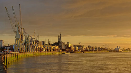 River by buildings against sky during sunset