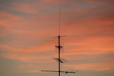 Low angle view of weather vane against cloudy sky