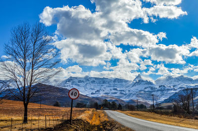 Road by bare tree against cloudy sky during winter