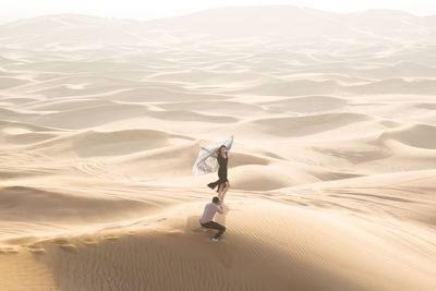 High angle view of man photographing woman at desert