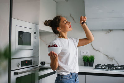 Happy nutritionist woman holds a fresh cherry berry in a plate in her hand. the concept of healthy 