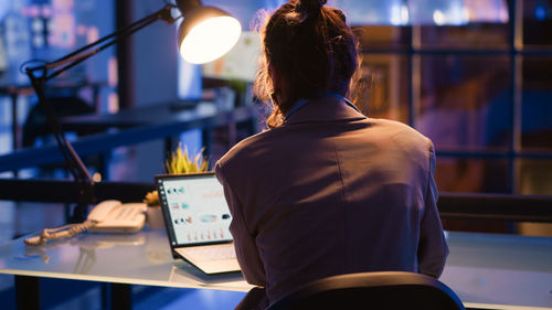 Rear view of young woman using mobile phone in office